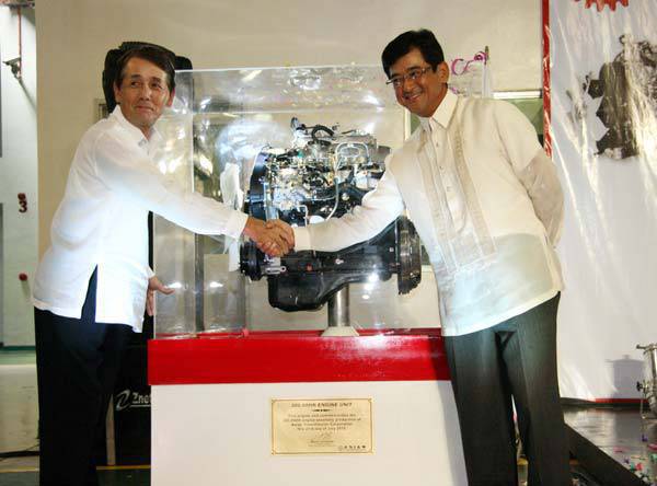 TopGear.com.ph Philippine Car News - Mitsubishi Motors Philippines president and chief executive Masahiko Ueki and Asian Transmission president and chief executive Kenji Ichimiya pose behind the 300,000th engine unit during the milestones celebration at Asian Transmission’s plant in Calamba, Laguna.